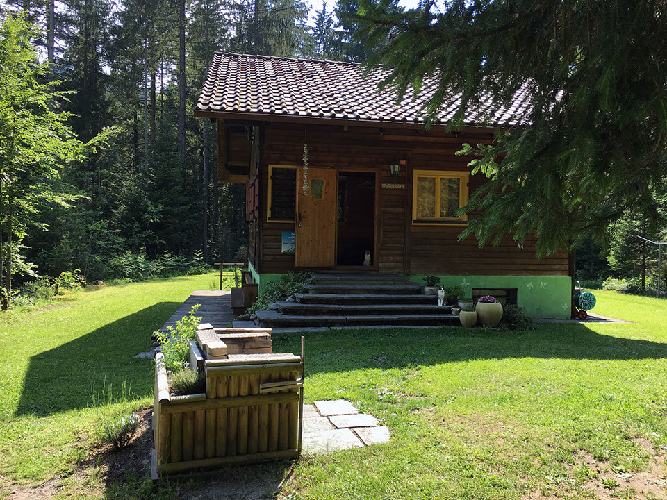 Die Stube des Waldfrieden Ferienhauses verfügt über einen grossen Holztisch und eine Eckbank.